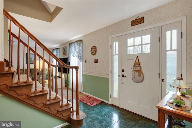 foyer featuring stairs, dark tile patterned flooring, and wallpapered walls