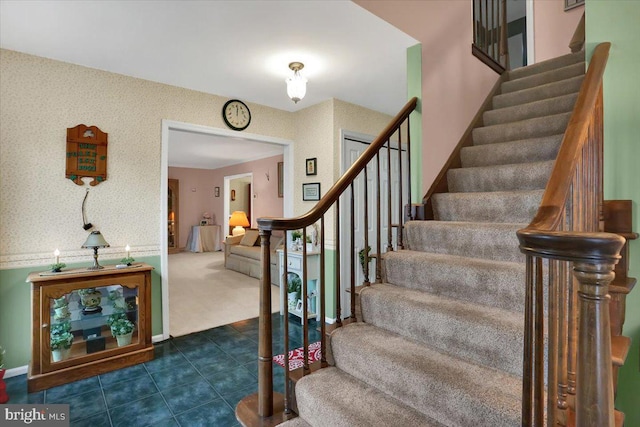 staircase with baseboards, carpet, tile patterned floors, and wallpapered walls