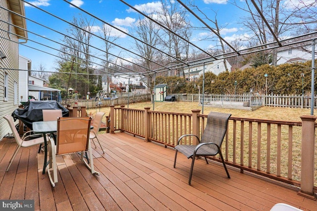 wooden terrace featuring outdoor dining area, a yard, a storage shed, a fenced backyard, and an outdoor structure