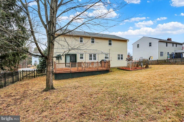 back of house with a fenced backyard, a lawn, and a wooden deck