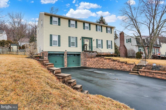 view of front facade with a garage, brick siding, driveway, a residential view, and a chimney