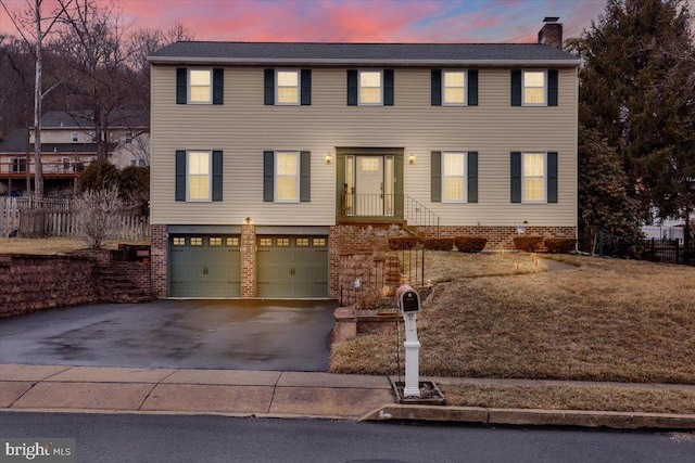 view of front of property with an attached garage, a chimney, and aphalt driveway