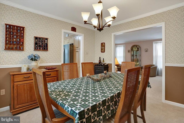 dining space featuring wallpapered walls, ornamental molding, an inviting chandelier, and light colored carpet