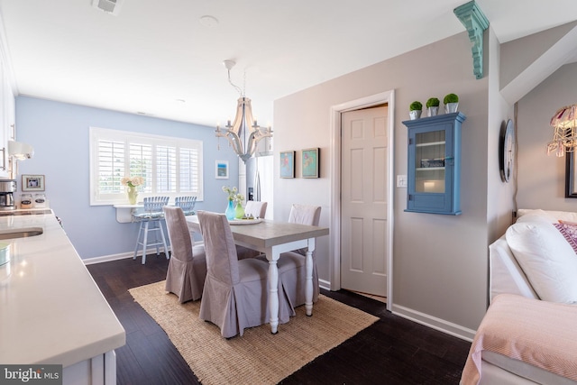 dining space featuring dark wood-style flooring, a notable chandelier, and baseboards