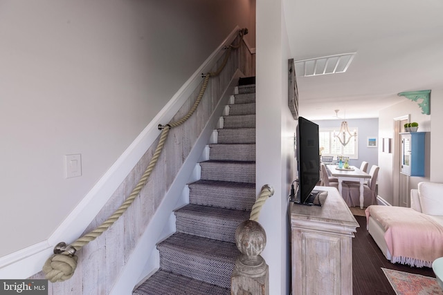 stairs with a chandelier and wood finished floors