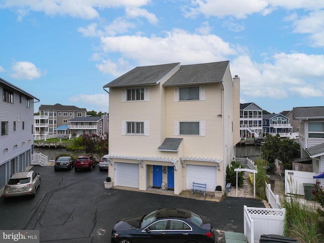 multi unit property featuring a chimney, an attached garage, fence, and a residential view