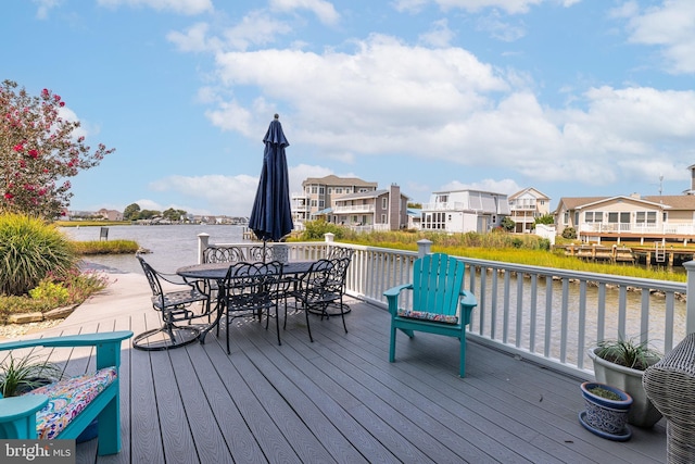 wooden terrace featuring outdoor dining space, a water view, and a residential view