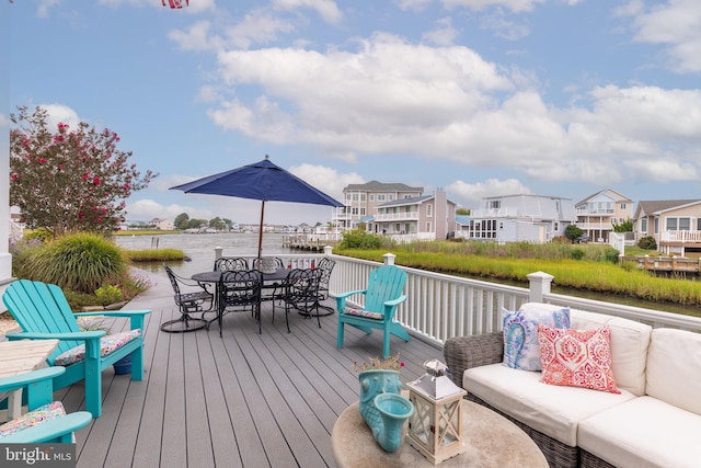 wooden terrace featuring a water view, outdoor dining area, a residential view, and an outdoor hangout area