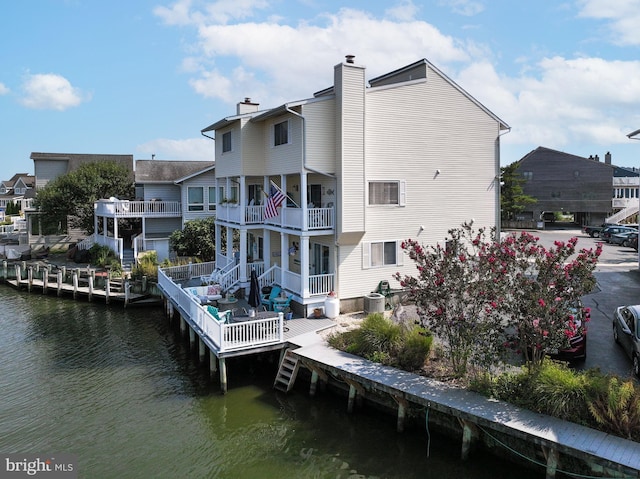 rear view of property featuring a chimney, a water view, a balcony, and central air condition unit