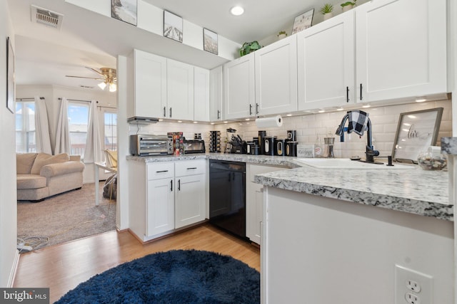 kitchen with dishwasher, a sink, visible vents, and white cabinetry