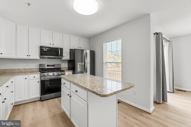 kitchen with light wood-style floors, appliances with stainless steel finishes, and white cabinets