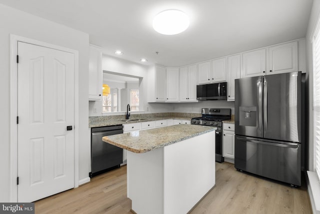 kitchen with a sink, appliances with stainless steel finishes, light wood-style floors, and white cabinets