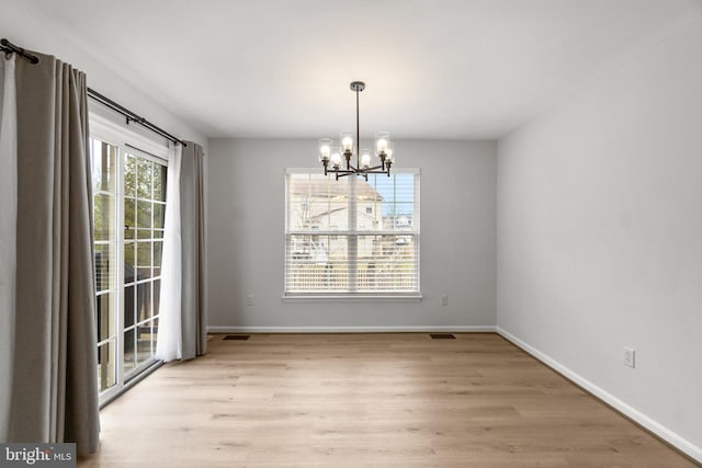 unfurnished dining area with baseboards, wood finished floors, visible vents, and a notable chandelier