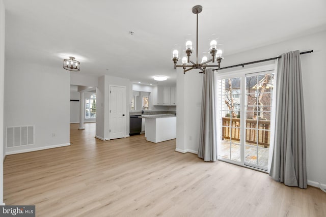 unfurnished dining area with a chandelier, light wood-style flooring, visible vents, and baseboards