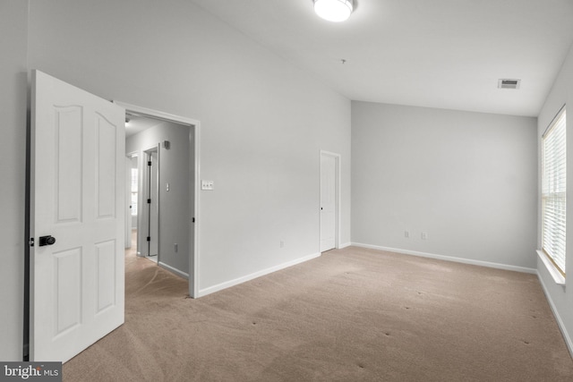 unfurnished room featuring lofted ceiling, carpet, visible vents, and baseboards