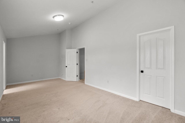 unfurnished room featuring high vaulted ceiling, baseboards, and light colored carpet