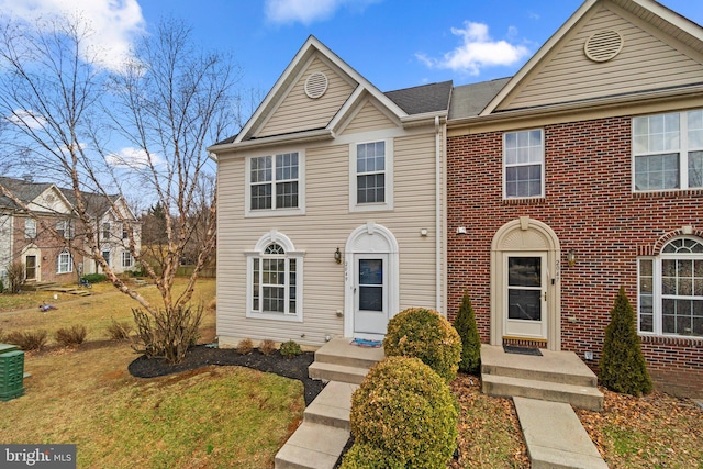 view of property featuring brick siding and a front yard