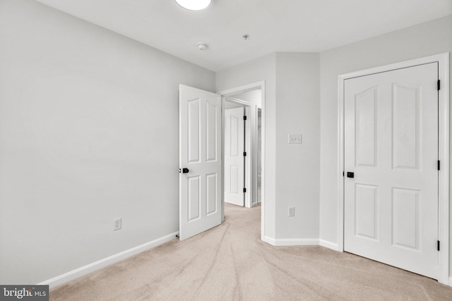 unfurnished bedroom with light carpet and baseboards