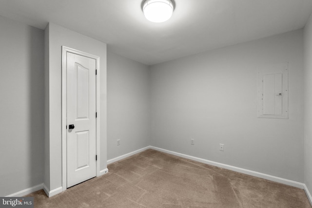 unfurnished room featuring light colored carpet, electric panel, and baseboards