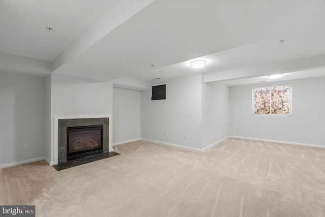 below grade area featuring a fireplace with flush hearth, baseboards, and light colored carpet