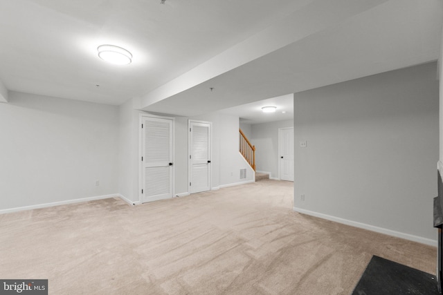 finished below grade area featuring carpet flooring, visible vents, baseboards, and stairs