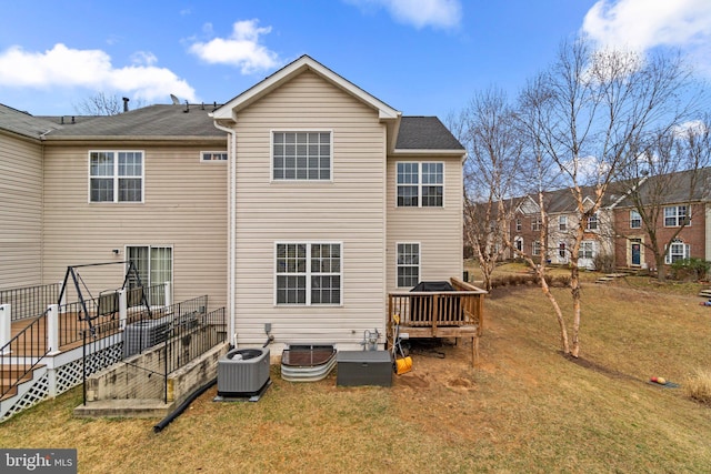 rear view of house with central AC unit, a deck, and a yard