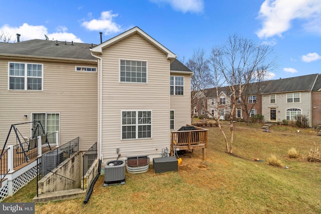 rear view of property with central air condition unit, a deck, and a yard