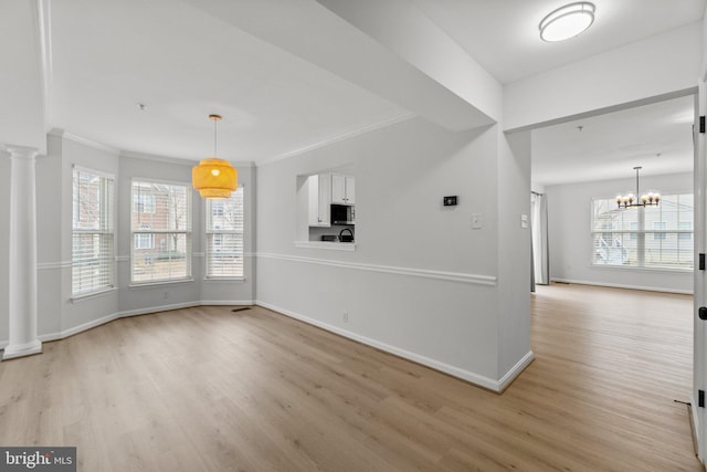 interior space featuring light wood-type flooring, baseboards, crown molding, and ornate columns