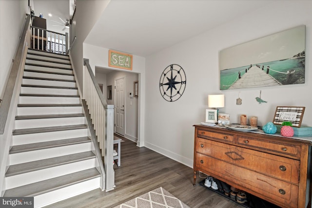 foyer with a ceiling fan, baseboards, stairway, and wood finished floors