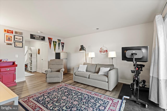 living room featuring baseboards, visible vents, arched walkways, and wood finished floors