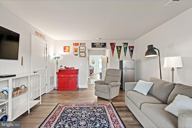 living area with visible vents and wood finished floors