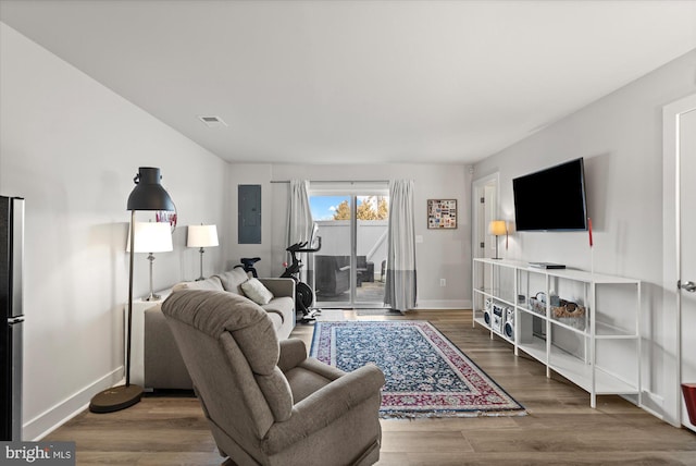 living room featuring visible vents, wood finished floors, electric panel, and baseboards