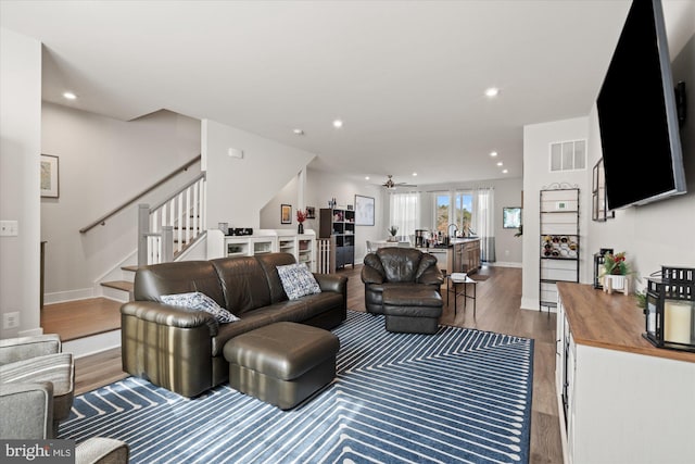 living area featuring light wood-style flooring, recessed lighting, visible vents, baseboards, and stairs