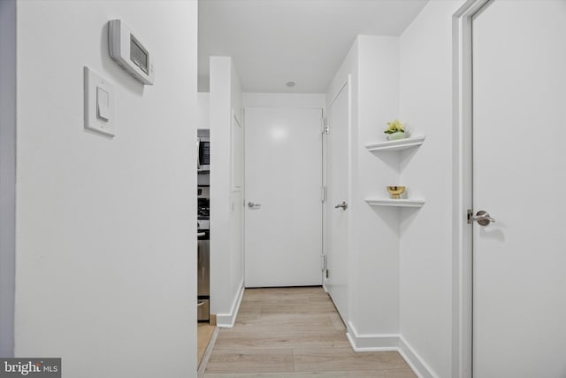 hall with light wood-type flooring and baseboards