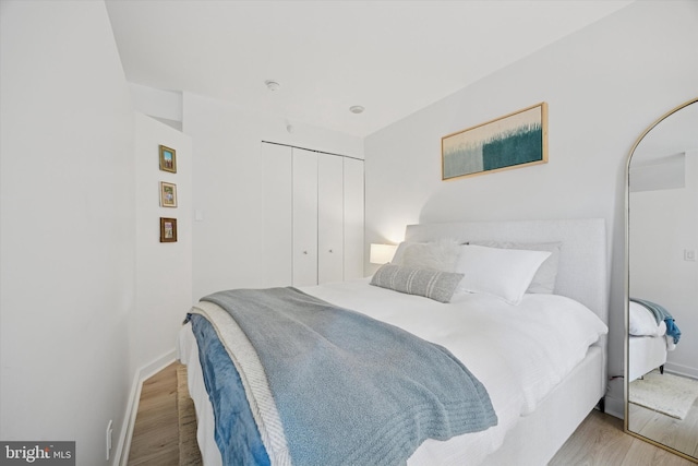 bedroom featuring a closet, wood finished floors, and baseboards