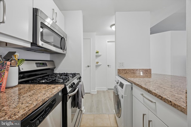 kitchen featuring washer / dryer, white cabinets, stainless steel appliances, and light stone counters