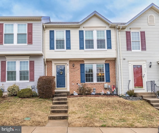 townhome / multi-family property featuring a front yard and brick siding