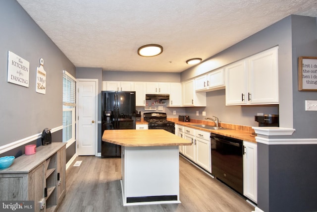 kitchen featuring black appliances, a sink, white cabinets, and under cabinet range hood