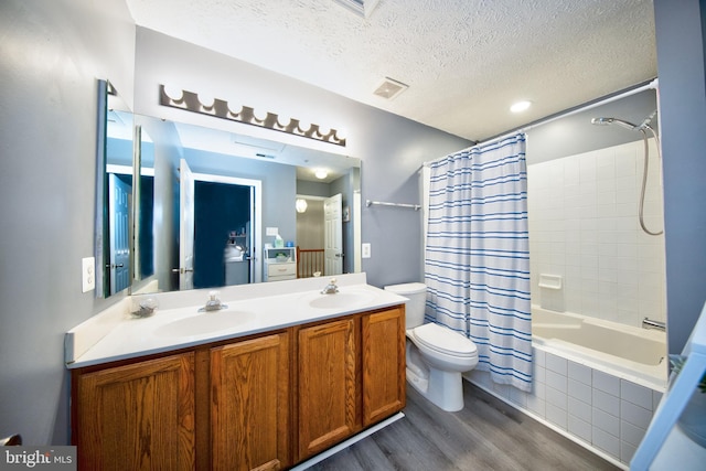 full bathroom with toilet, a textured ceiling, a sink, and wood finished floors