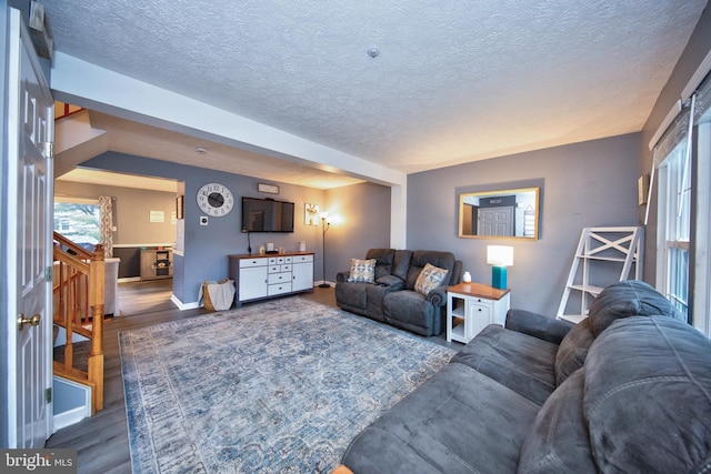 living room with a textured ceiling, baseboards, and wood finished floors