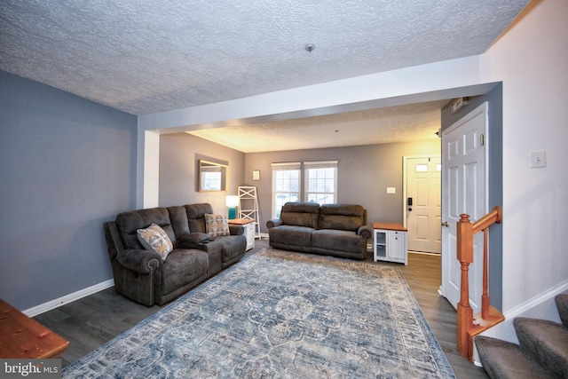 living room featuring stairs, a textured ceiling, wood finished floors, and baseboards