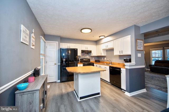 kitchen with black appliances, light wood-style flooring, white cabinetry, and under cabinet range hood