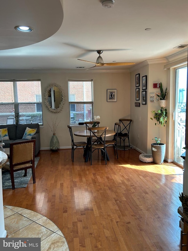 dining area featuring light wood finished floors, ornamental molding, visible vents, and baseboards