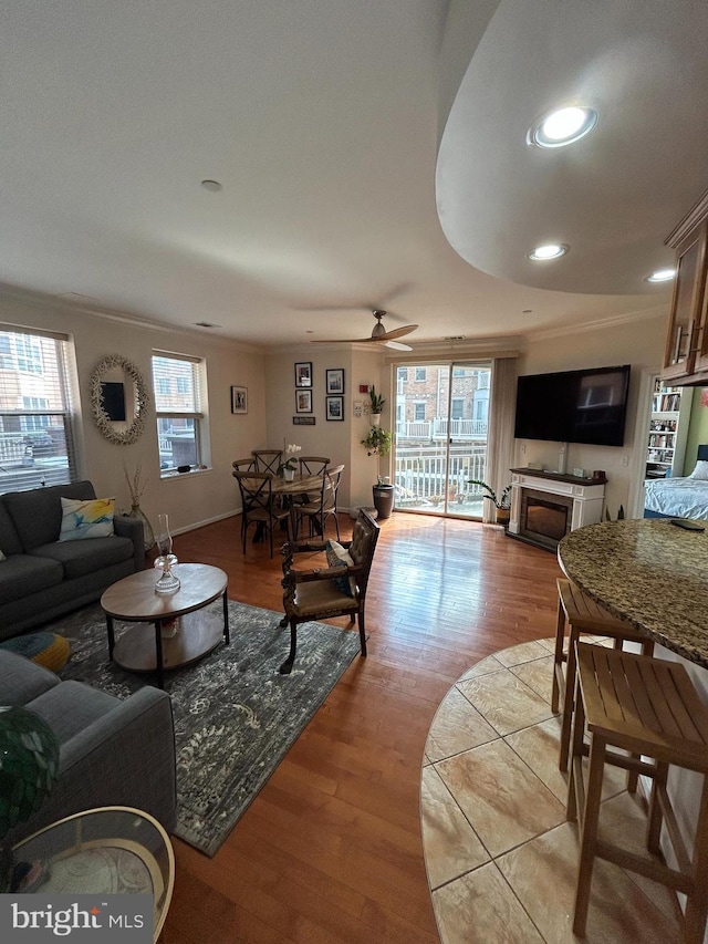 living room featuring a ceiling fan, recessed lighting, crown molding, and light wood-style flooring