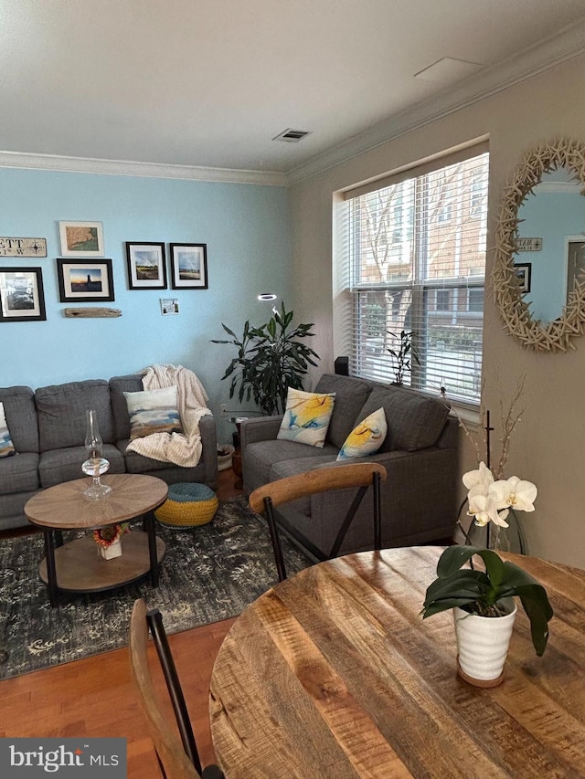 living room with ornamental molding, visible vents, and wood finished floors