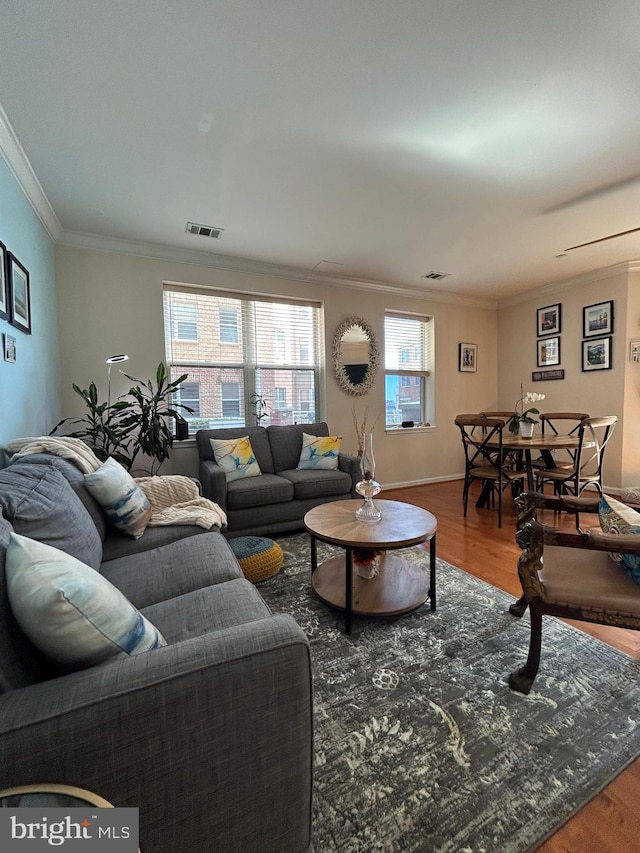 living area featuring baseboards, crown molding, visible vents, and wood finished floors