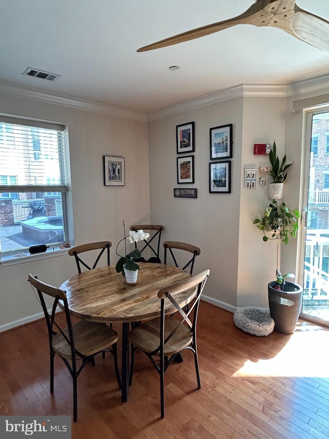 dining room featuring baseboards, light wood-style floors, visible vents, and crown molding