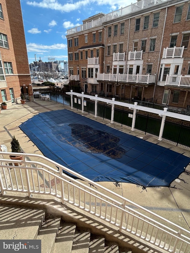 pool with a view of city, a patio area, and fence