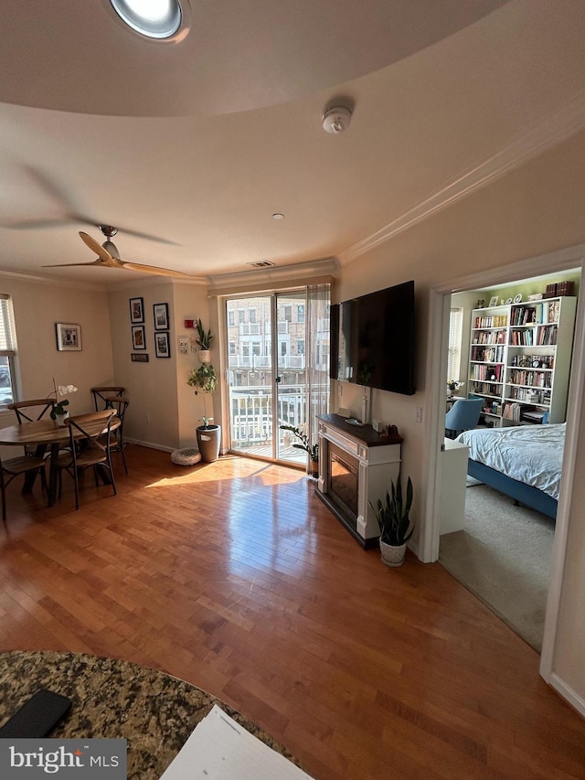 living room featuring ornamental molding, a ceiling fan, and wood finished floors