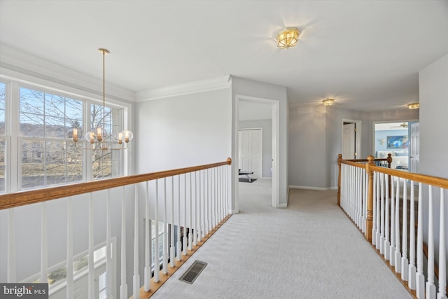 corridor with baseboards, carpet flooring, visible vents, and an inviting chandelier